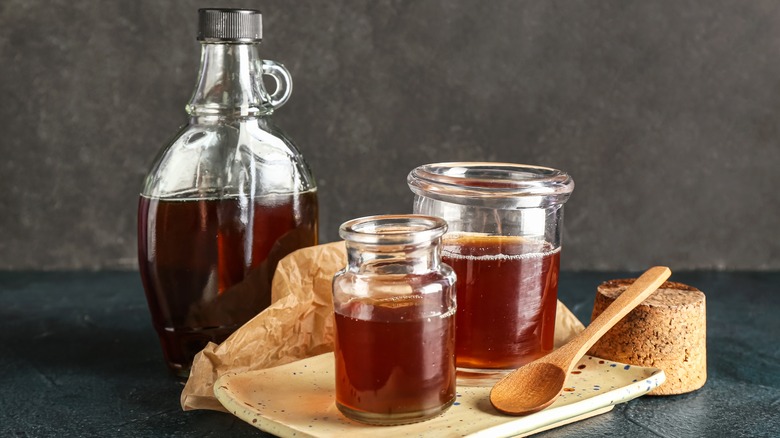 jug of maple syrup with two smaller jars of maple syrup