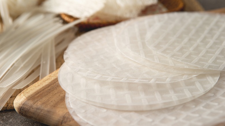 a stack of rice paper on a wooden cutting board