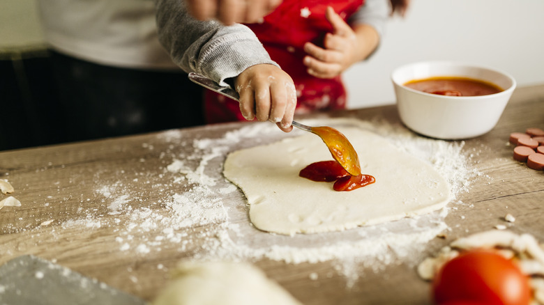 Spreading sauce on pizza dough