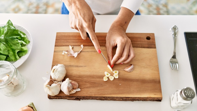 person chopping garlic on cutting board