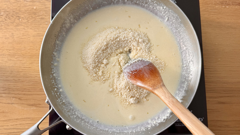 Grated Parmesan cheese stirring into cream sauce