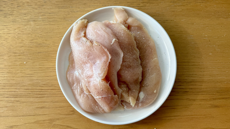 Raw chicken breasts seasoned with salt and pepper