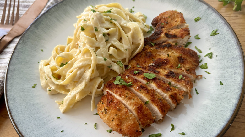 Fettuccine Alfredo and sliced chicken on plate