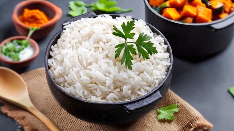 A cast iron bowl of white rice and other dishes