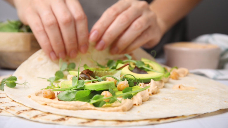 Person making a hummus wrap