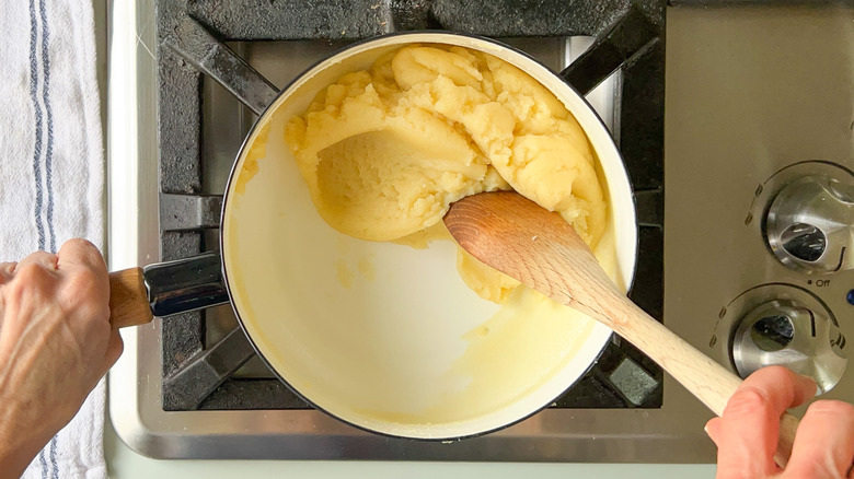 Cooking gougerè dough in saucepan with wooden spoon