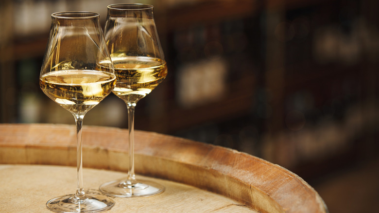 Two glasses of white wine on a barrel.