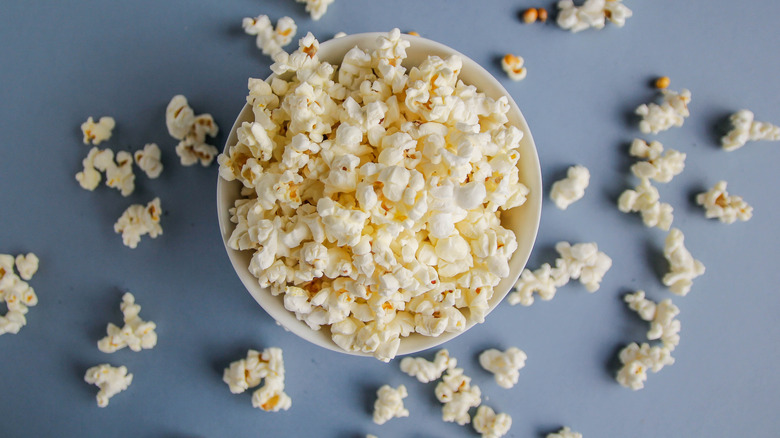 Bowl of popcorn on counter with spilled popped kernels