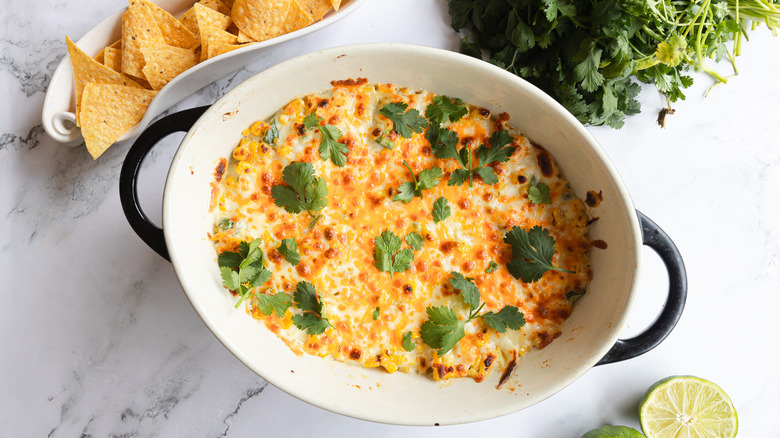 Corn dip with chips, limes and cilantro