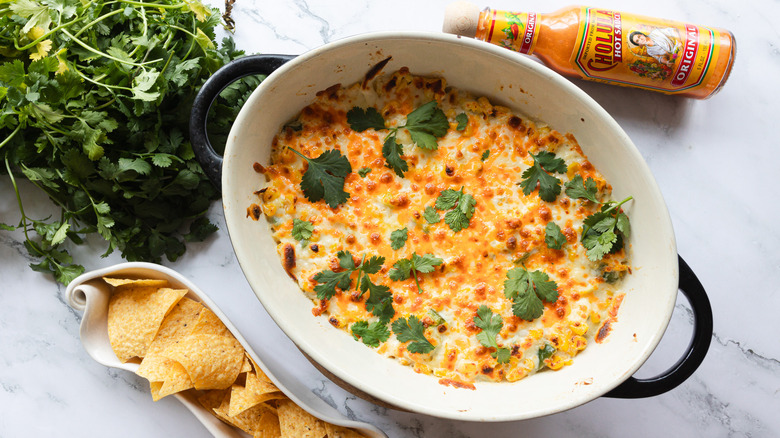 Cheesy corn dip with cilantro, chips and limes