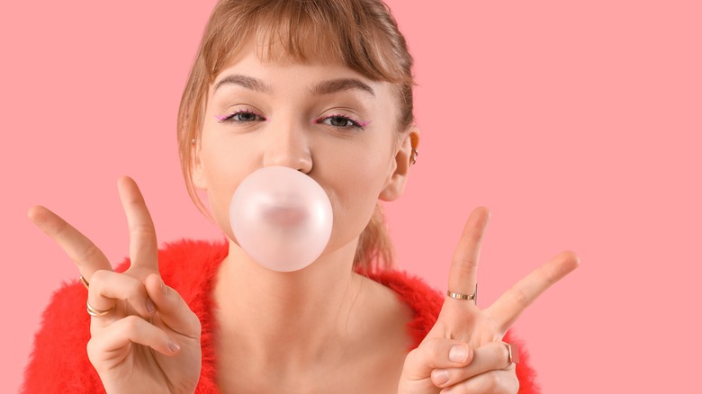 Girl blowing a pink bubblegum bubble