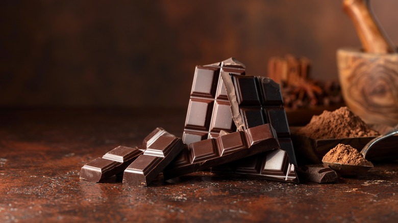 Chocolate bars and cocoa powder on brown surface