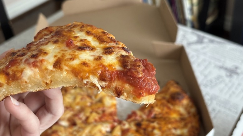 piece of Domino's pizza showing tomato sauce on tip