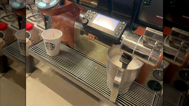 Espresso maker dripping coffee and steaming milk