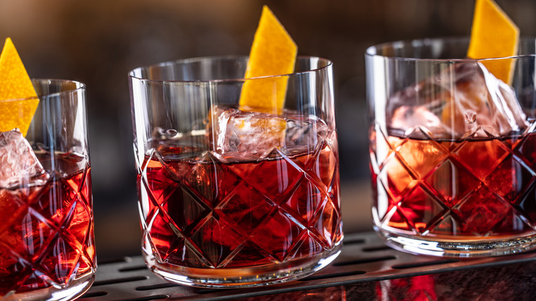 A row of vibrant Negronis in pretty glassware.