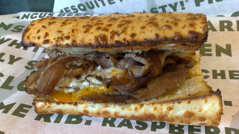 Toasted Quiznos steak sandwich on paper wrapping.