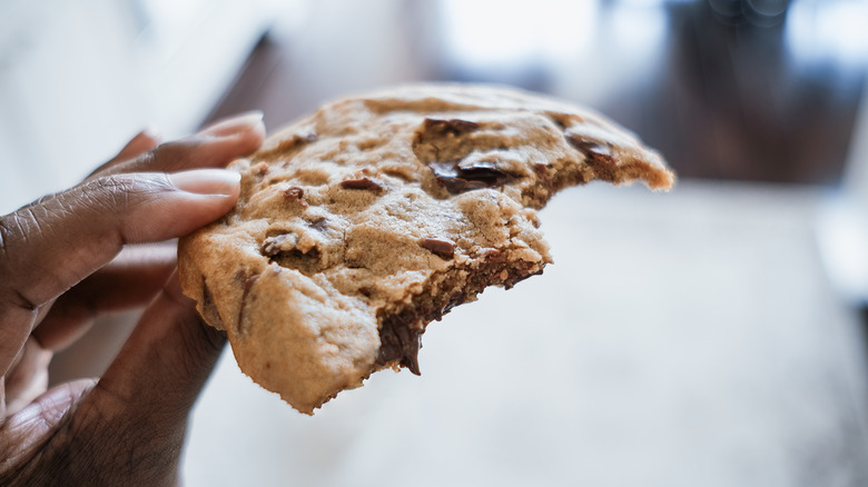 Hand holding a cookie that has been half bitten off.