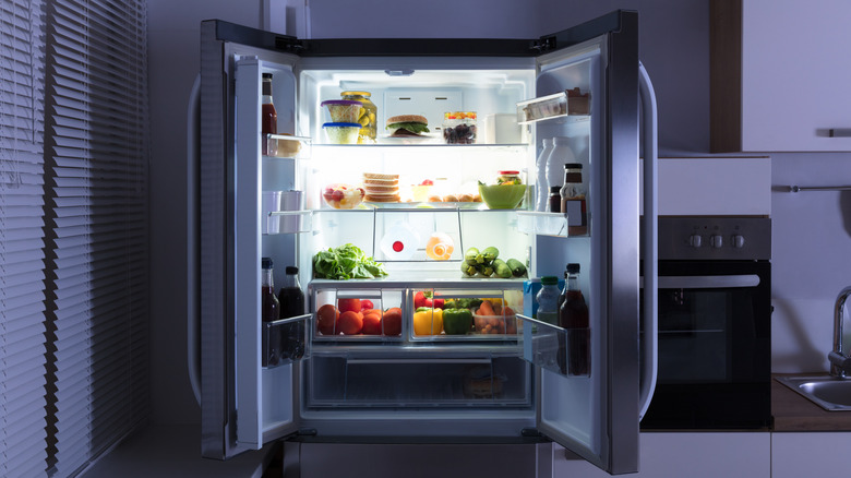 Dual door refrigerator with top doors open in dark kitchen