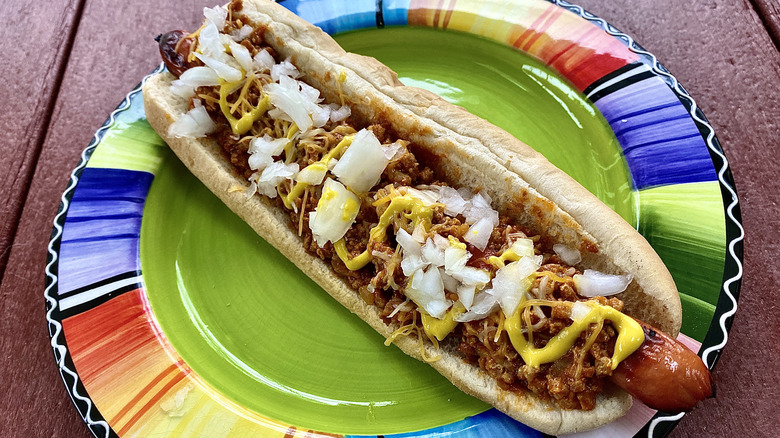 A foot long chili dog topped with onions and cheese