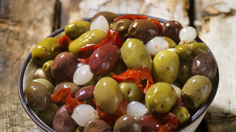 A bowl of olives with pearl onions and peppers