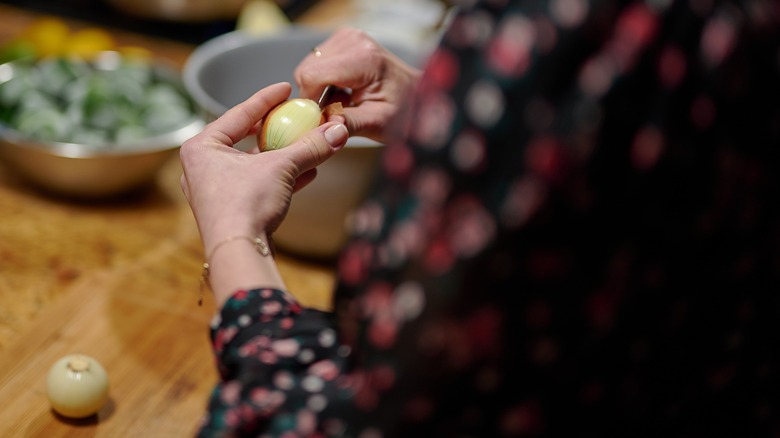 Woman peeling large pearl onions with a knife