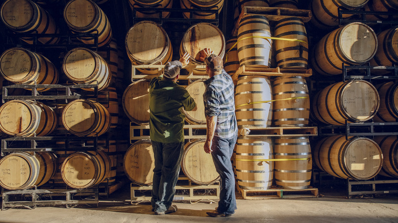 Two men in front of whiskey barrels