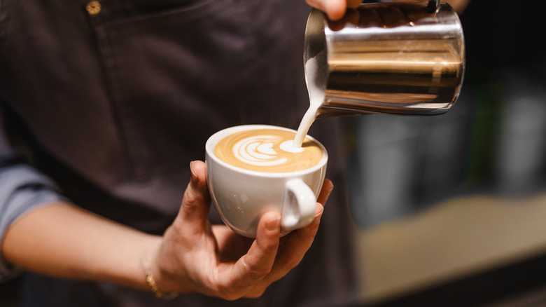 Pouring milk foam in latte