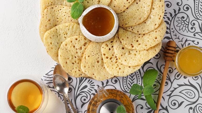 A plate of Moroccan baghrir with tea and honey.