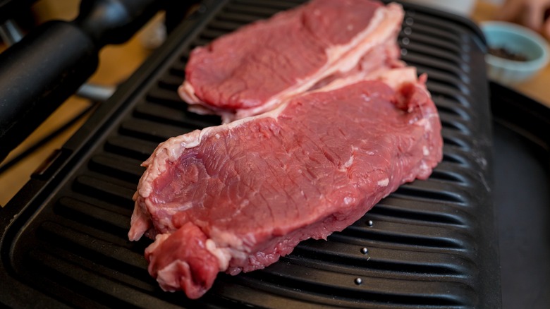 raw steak on grill