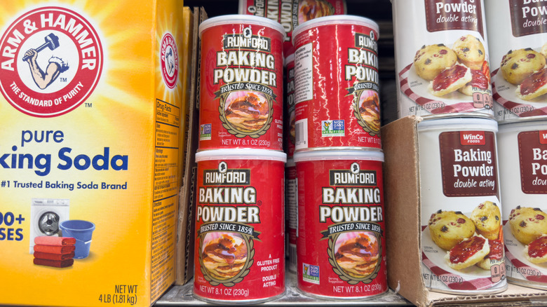 baking soda and baking powder containers sit next to each other on a shelf