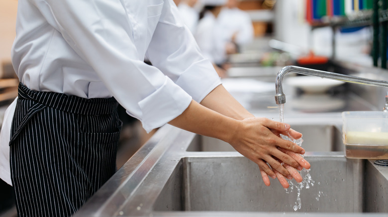 A person washing their hands in a restaurant kitchen