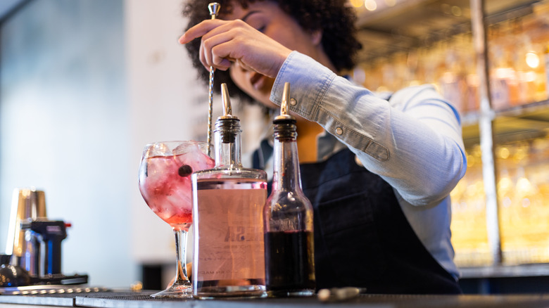 bartender stirring cocktail at bar