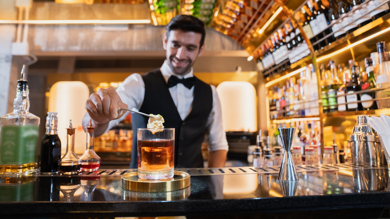 Bartender garnishing a whiskey cocktail