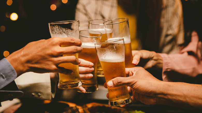 Several hands toast with glasses of beer.