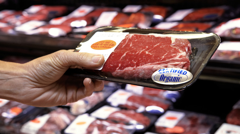 A man picking up a steak labeled organic