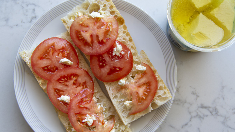 slices of tomato on two slices of baguette bread on a white plate