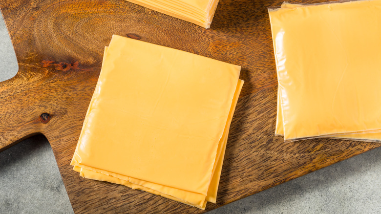 stacks of American cheese on wooden cutting board