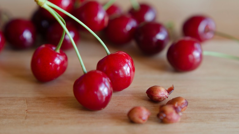 Red cherries and cherry pits on a wooden surface