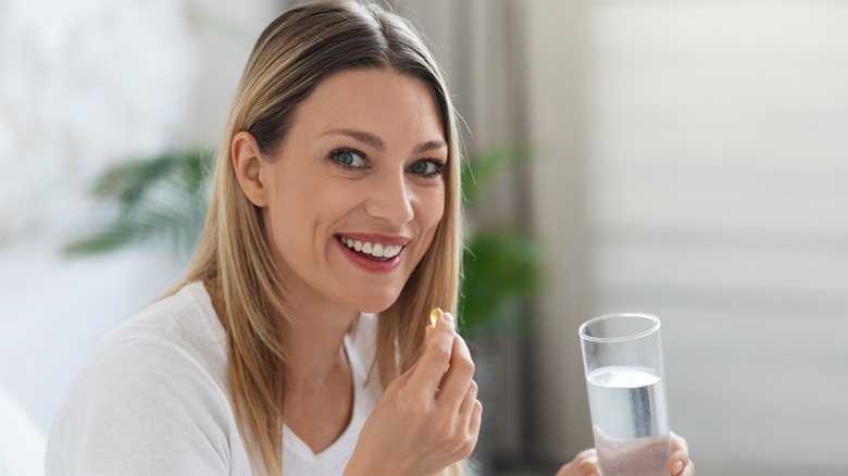 Woman holding glass and vitamin