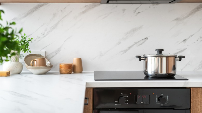 a pot sitting on a glasstop cooking hob in a ceramic accented kitchen