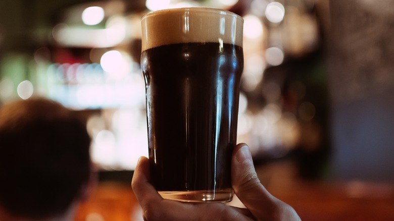 Person holding porter beer in glass