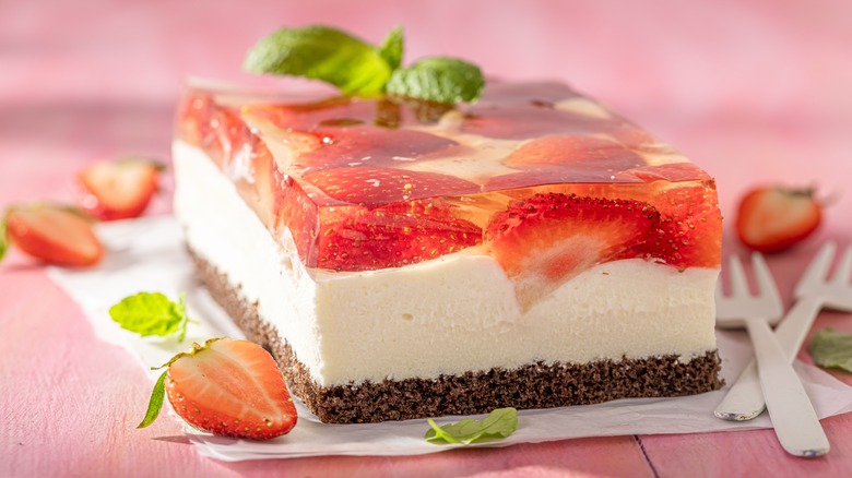 Rectangular strawberry jelly cheesecake with forks on a pink background