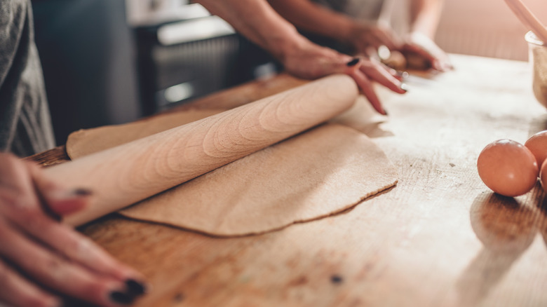 person using rolling pin on dough