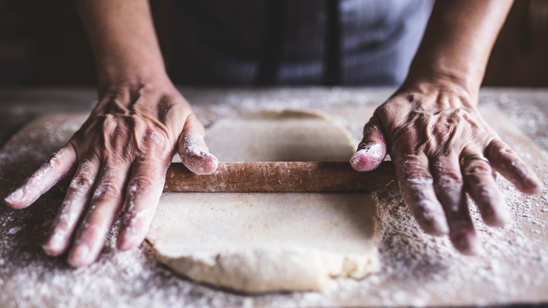 person using straight rolling pin on dough