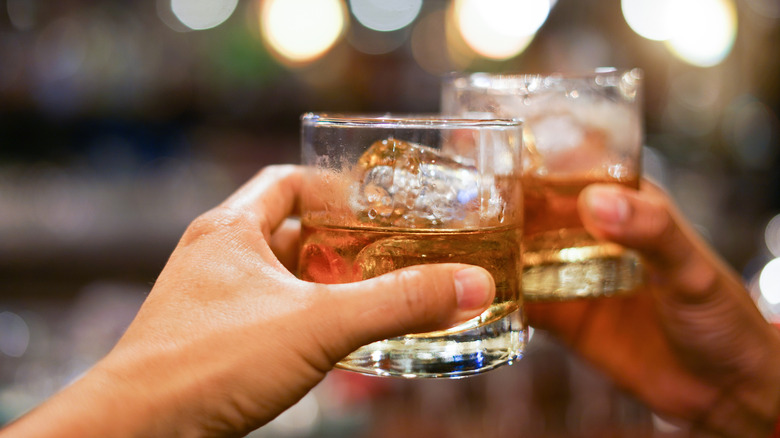 Two people toasting with whiskey