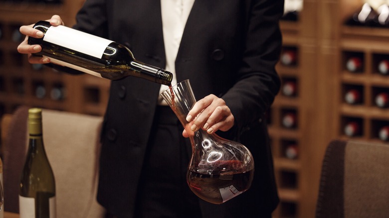 Sommelier slowly decanting wine into a shaft and globe decanter