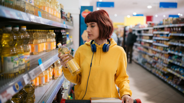 young woman with red hair in grocery store buying cooking oil