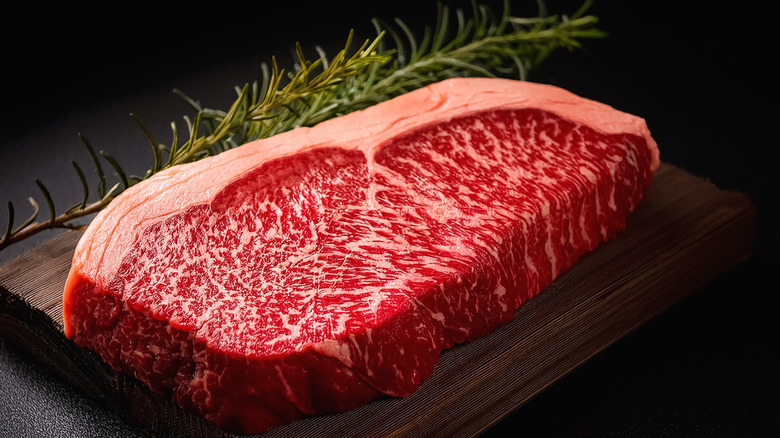 Raw, marbled steak on cutting board