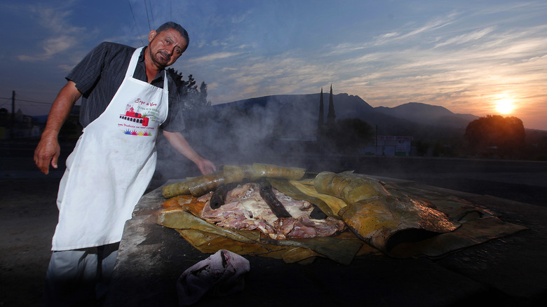 Person cooking barbacoa in pit