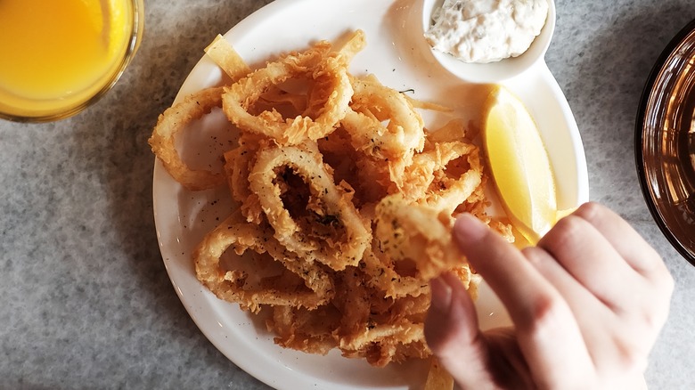 hand reaching for calamari ring